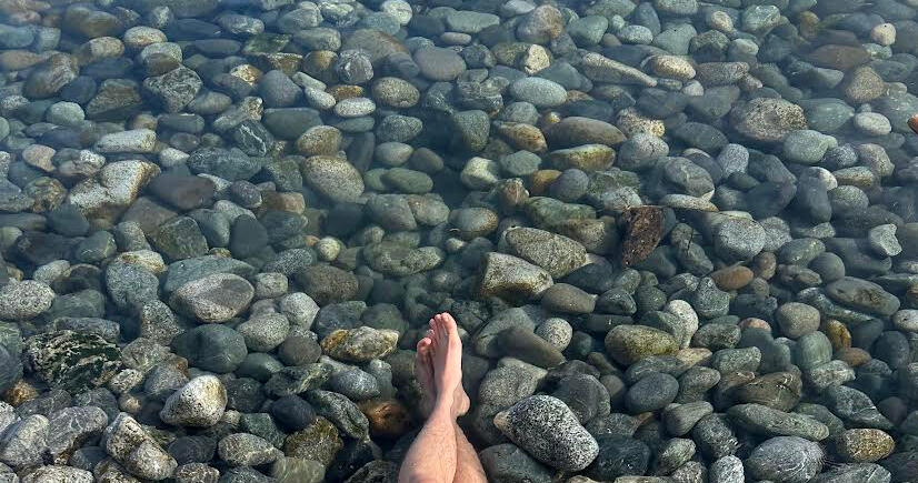 The Salish Sea Big pebbles/rocks in the Salish Sea. Legs are visible in the water, with someone clearly sitting off camera in the sea.